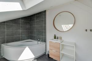 a bathroom with a white tub and a mirror at Cocon au fond du jardin in Souffelweyersheim