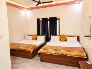 two beds in a small room with blue curtains at Hotel Ramkesarrai in Ayodhya +27 photos