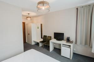 a room with a desk with a computer and a television at Alex&George Boutique Hotel in Cluj-Napoca +29 photos