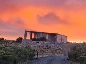 a house on top of a hill with a dirt road at Oudam Cottage in Carnarvon