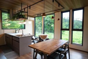 a kitchen with a wooden table and some windows at STARRY The Garden Hakuba Iwatake in Hakuba
