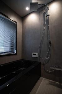 a bathroom with a shower with a black tub at STARRY The Garden Hakuba Iwatake in Hakuba