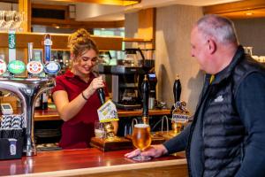 a woman pouring a man a drink at a bar at Patterdale Hotel in Patterdale