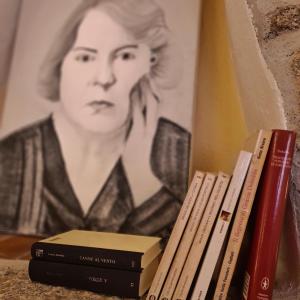 a pile of books sitting on a shelf next to a painting at Al Vecchio Corso B&B in Tempio Pausania