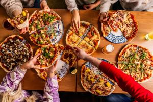 a group of people sitting around a table eating pizza at Patterdale Hotel in Patterdale