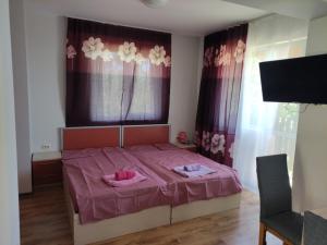 a bedroom with a pink bed with two towels on it at Miranis in Byala
