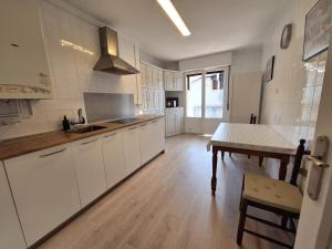 a kitchen with white cabinets and a wooden table at Apartamento ARBEA in Ochagavía