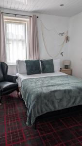 a bedroom with a large bed and a chair at Ocean Breeze Inn in Eyemouth