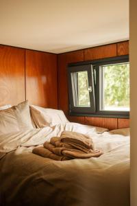 a pile of towels laying on a bed with a window at The Creative Boat - Sneekermeer in Offingawier