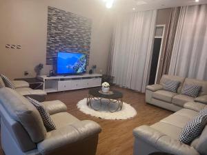 a living room with couches and a flat screen tv at Cameo Villa in Kigali