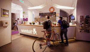 two people standing at a counter with a bike at Wombat's City Hostel Budapest in Budapest