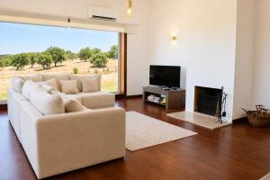 a living room with a white couch and a television at Pouso Du'Vagar in Cuba