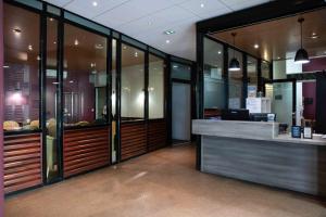 an office with a reception desk and glass walls at Ténéo Apparthotel Bordeaux - Gare Saint Jean in Bordeaux