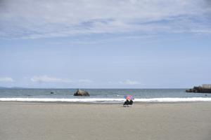 a person standing on a beach with an umbrella at 大磯シーサイドハウス 海まで2分 駅近の一軒家 in Oiso