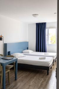 a bedroom with two beds and a table and a window at Ténéo Apparthotel Bordeaux - Gare Saint Jean in Bordeaux +40 photos