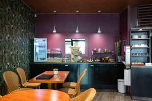 a kitchen with purple walls and wooden tables and chairs at Ténéo Apparthotel Bordeaux - Gare Saint Jean in Bordeaux