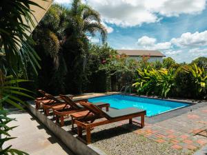 a swimming pool with lounge chairs next to a swimming pool at Ethera Arugam bay in Arugam Bay