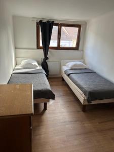 two beds in a small room with a window at myappart - FORBACH in Forbach +3 photos
