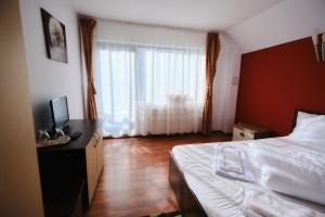 a bedroom with a bed and a desk with a television at Vila Residence in Moieciu de Sus