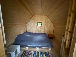 a small room with a bed in a wooden cabin at Cabanele din RÂTUL FLORILOR in Hotar