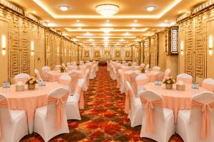 a row of tables in a banquet hall with white bows at Mazestic Bay Hotel & Banquet in Noida