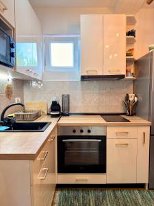 a kitchen with white cabinets and a stove top oven at Kuca za odmor SONATA in Biserske Kuće +11 photos