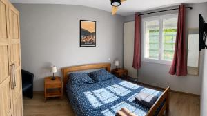 a bedroom with a bed with a blue comforter and a window at Entre Mer et Montagnes in Céret
