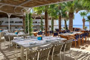 a restaurant with tables and chairs and palm trees at Parklane, a Luxury Collection Resort & Spa, Limassol in Limassol