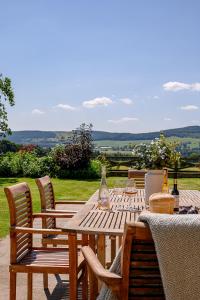 a wooden table with chairs and wine bottles on it at Hollins Farmhouse in Leyburn