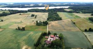 an aerial view of a field with a house and a kite at Siedlisko Żywe Kamienie in Naguszewo