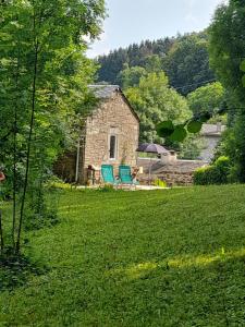 a stone house with two blue chairs in a yard at Rossignol in Le Bez