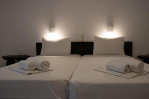 two beds with white sheets and towels on them at Paradise Beach Apartments in Argassi