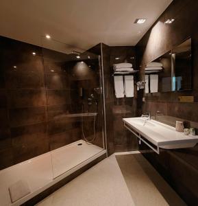 a bathroom with a shower and a sink and a tub at Hôtel de La Cloche in Dole +22 photos