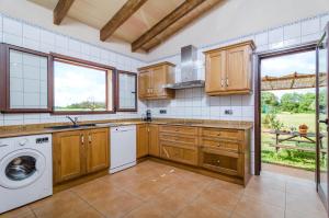 a kitchen with wooden cabinets and a washer and dryer at Son Fred in Felanitx