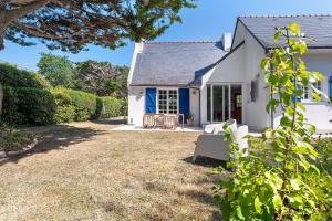 a white house with a blue door and a yard at Ker Family in Arzon