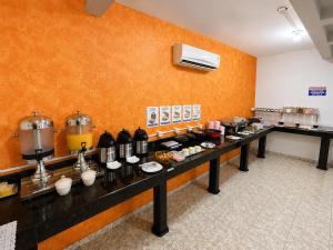 a kitchen with a long table with food on it at Alfa Hotel Nova Mutum in Nova Mutum +8 photos