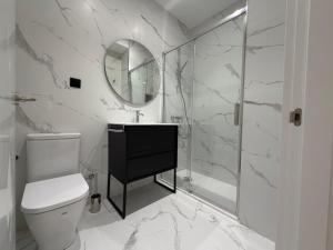 a bathroom with a toilet and a sink and a mirror at MTM Rooms in Santander