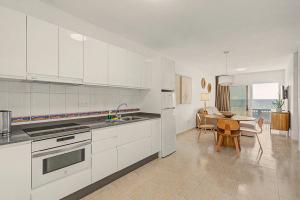 a kitchen with white cabinets and a table with chairs at Callao Beach 1 in Arrieta +18 photos