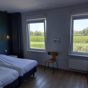 a bedroom with two beds and a chair and two windows at Het Wapen van Harmelen in Harmelen
