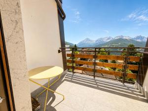 a balcony with a table and a view of mountains at Hostdomus - Villaggio Alpino in Sauze d'Oulx