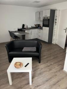 a living room with a black couch and a table at Ferienwohnung Krayenbergblick 1 in Bad Salzungen +3 photos