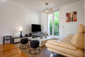 a living room with a couch and a tv at Maison La Mirabelle in Thann