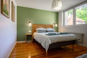 a bedroom with a bed with green walls and a window at Maison La Mirabelle in Thann
