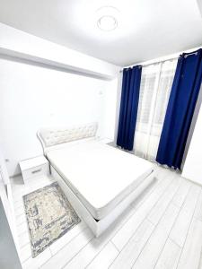 a bedroom with a white bed and blue curtains at Apartament Militari in Chiajna