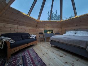 a bedroom with a bed and a couch in a cabin at Lavvo med glasstak in Svenseid