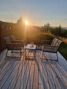 two chairs and a table on a deck with the sunset at Lavvo med glasstak in Svenseid