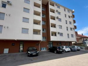 a large apartment building with cars parked in a parking lot at Teslić CITY Apartment in Teslić