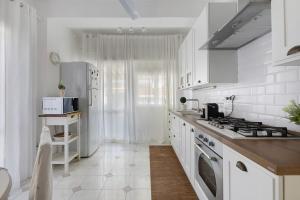 a white kitchen with a stove and a refrigerator at A due passi dal mare in Oliveri