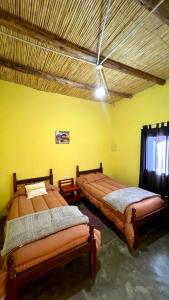 two beds in a room with a yellow wall at Casa Manuel in Tinogasta