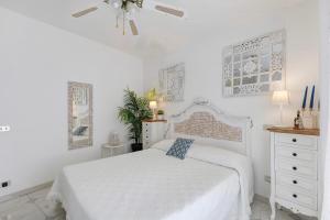 a white bedroom with a bed and a ceiling fan at A due passi dal mare in Oliveri